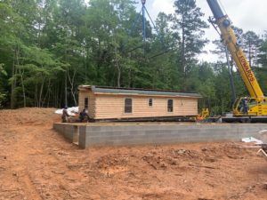crane lifts the modular section of the log home onto the foundation